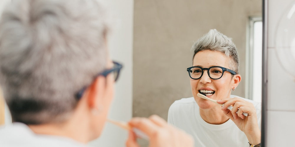 woman brushing teeth with bamboo toothbrush 