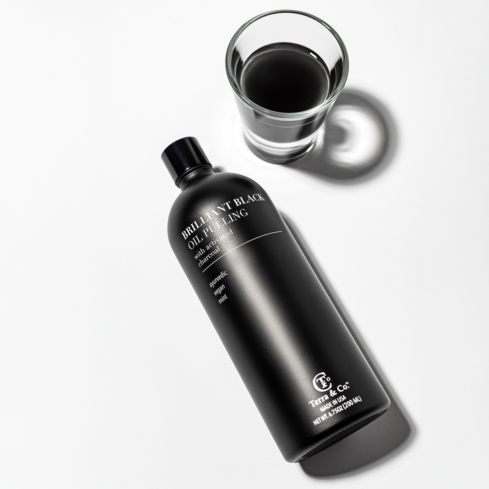 Close-up of Brilliant Black Oil Pulling bottle and dark black oil texture, showcasing activated charcoal and nutrient-rich formula