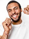 Man using Terra & Co. Brilliant Black® Dental Floss in front of mirror, part of natural and holistic oral hygiene routine