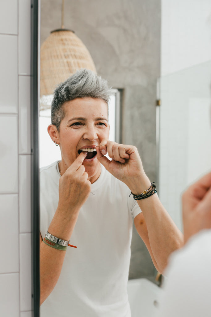 Woman using Terra & Co. plant-based dental floss with coconut oil and bamboo fiber for clean, white teeth
